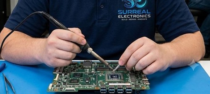 Soldering a laptop motherboard at the Surreal Electronics bench